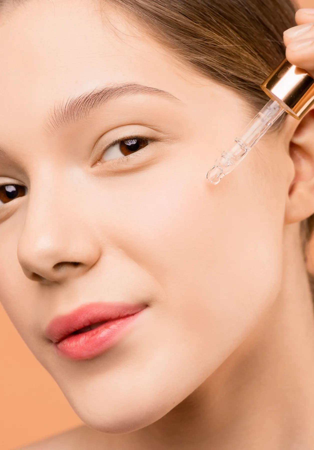 Altın damlalıkla yüzüne serum uygulayan kadın